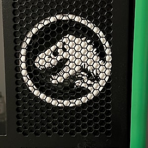 May include: Black computer case with a honeycomb mesh design. A white circular graphic of a stylized animal is visible through the mesh. The case has a green accent on the side.