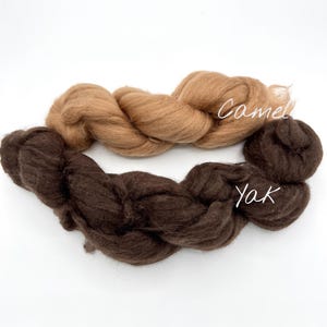 May include: Two bundles of fiber, one light brown and one dark brown, are displayed against a white background. The light brown fiber is labeled "Camel," and the dark brown fiber is labeled "Yak."