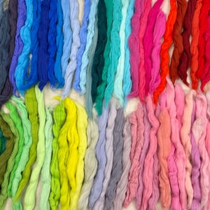 May include: A collection of colorful yarn strands in various shades of blue, green, yellow, orange, red, pink, and purple. The yarn is arranged in rows, creating a rainbow effect.