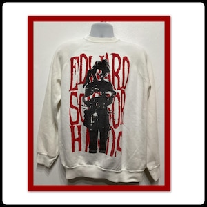 May include: White sweatshirt featuring a black and red graphic of Edward Scissorhands. The graphic includes the film's title in red, stylized lettering. The sweatshirt is displayed on a mannequin.