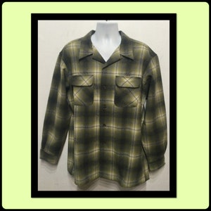 Puede incluir: Una camisa de manga larga a cuadros con un frente abotonado con cuello. La camisa es verde y negra con un patrón de cuadros blancos.