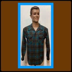 Può includere: Camicia a quadri a maniche lunghe nei toni del marrone e del verde acqua, esposta su un manichino. La camicia presenta due tasche sul petto e un colletto classico. Il motivo a quadri è un mix di verde acqua e marrone.