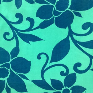 May include: A close-up of a fabric with a repeating floral pattern. Large, stylized flowers and leaves in a deep teal color are set against a light teal background. The design features curved stems and swirling accents.