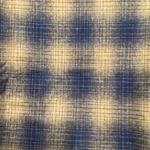 Puede incluir: Una tela de cuadros azul y blanco con un aspecto desgastado sutil. La tela tiene una textura tejida y una apariencia suave y descolorida.