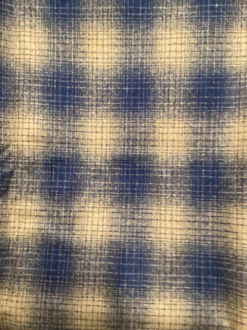 Puede incluir: Una tela de cuadros azul y blanco con un aspecto desgastado sutil. La tela tiene una textura tejida y una apariencia suave y descolorida.