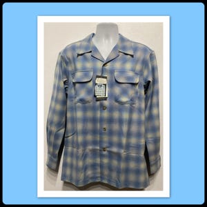 May include: A blue and white checked long-sleeved shirt with a button-down collar and two chest pockets. The shirt has a faded look and is made of a soft, comfortable fabric.