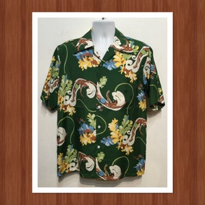 May include: A green short-sleeved shirt with a floral pattern. The flowers are yellow, white, and blue. The shirt has a button-up front.