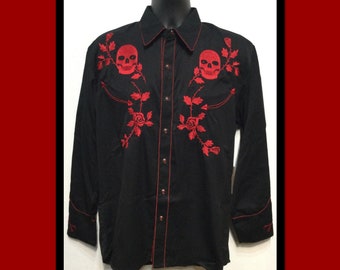 Può includere: Una camicia nera a maniche lunghe con bottoni, ricamata con teschi e rose rosse. La camicia ha un colletto in stile western e cuciture rosse.