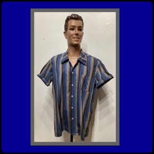 May include: A striped short-sleeved button-down shirt with a brown, blue, and white color scheme. The shirt has a collar and a pocket on the left side.