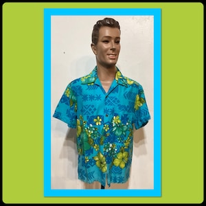May include: A short-sleeved, turquoise Hawaiian shirt with a floral pattern in yellow, green, and white. The shirt features a classic collar and button-down front. The shirt is displayed on a mannequin.