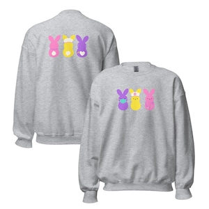 Peut inclure: Deux sweat-shirts gris avec un motif de trois lapins Peeps de couleur pastel portant des masques faciaux et un bonnet d'infirmière. Le motif du plus petit sweat-shirt est sur le devant, tandis que le motif du plus grand sweat-shirt est sur le dos.