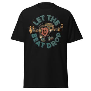 May include: Black t-shirt featuring a retro design with a heart-shaped character wearing headphones and holding a boombox. The text "LET THE BEAT DROP" is in a circle around the character, with musical notes scattered around the design.