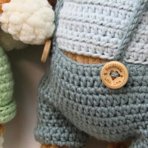May include: Close-up of a handmade crochet item in shades of blue and white. The item features a wooden button with the words "Handmade with Love" engraved on it. The crochet work has a textured appearance.