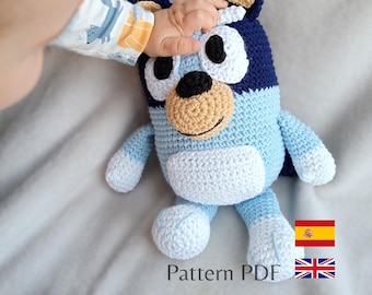 May include: A crocheted Bluey plush toy in shades of blue, white, and tan. The handmade toy features a detailed design with a light blue body, white belly and paws, and dark blue accents. The text "Pattern PDF" is visible at the bottom.