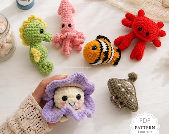 May include: A collection of handmade crochet sea creatures, including a seahorse, squid, clownfish, crab, and a clam with a smiling face. The toys are in various colors, such as green, pink, orange, red, and purple. A PDF pattern is also available.