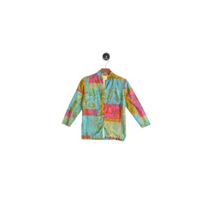 May include: A long-sleeved button-down shirt featuring a vibrant patchwork design with various rectangular panels in shades of turquoise, bright pink, mustard yellow, and orange, decorated with intricate floral and botanical patterns throughout.