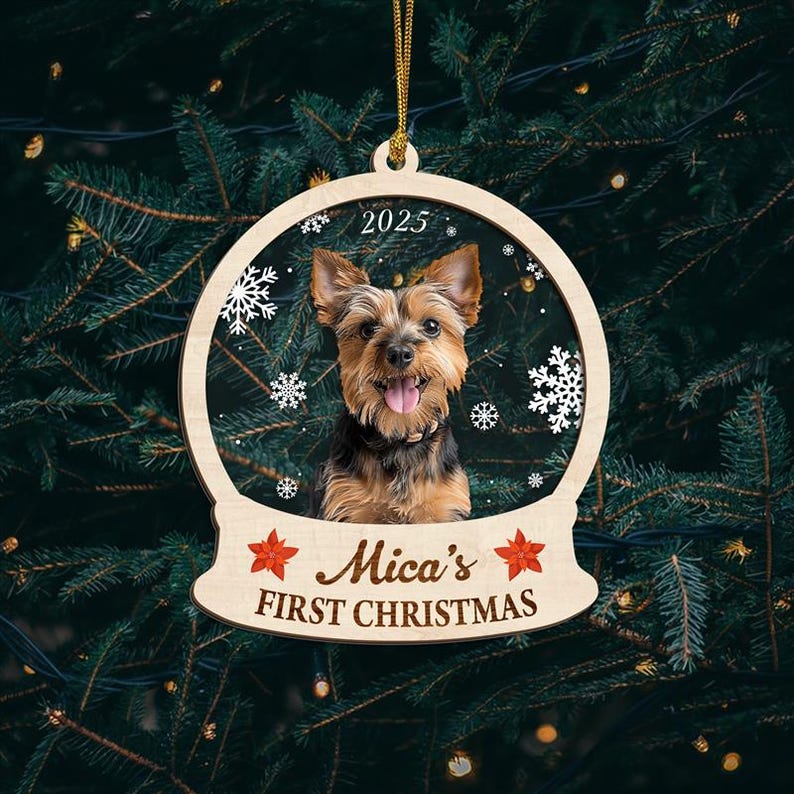 May include: A wooden Christmas ornament featuring a Yorkshire Terrier dog inside a snow globe design. The ornament has the text "2025" at the top and "Mica's FIRST CHRISTMAS" at the bottom, with red star accents. The ornament hangs from a gold string.