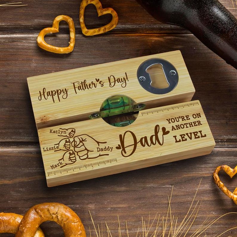 Pu&ograve; includere: Un apribottiglie e un raccogli tappi in legno con la scritta "Happy Father's Day!" e "Dad". L'apribottiglie ha un apribottiglie integrato e una livella. I nomi "Katlyn", "Lizzie" e "Mark" sono incisi sul legno.