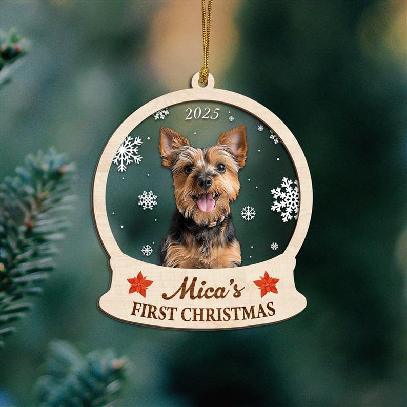 May include: Wooden Christmas ornament featuring a Yorkshire Terrier dog inside a snow globe design. The ornament has the text "Mica's FIRST CHRISTMAS" and the year "2025". The background is a dark green with white snowflakes.