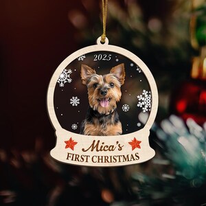 May include: Wooden Christmas ornament featuring a Yorkshire Terrier dog inside a snow globe design. The ornament includes the year 2025 and the text "Mica's FIRST CHRISTMAS" in a festive font, with snowflake and star accents.