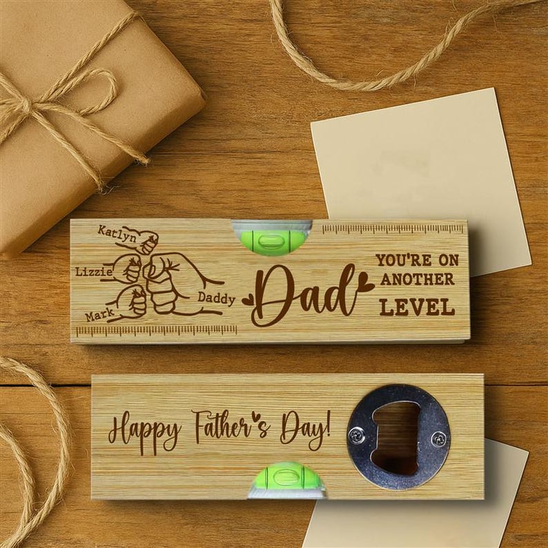 Pu&ograve; includere: Due regali di legno per la festa del pap&agrave;. Uno &egrave; una livella con la parola "Pap&agrave;" e la scritta "Sei a un altro livello". L'altro &egrave; un apribottiglie con la scritta "Buona festa del pap&agrave;!". Entrambi hanno una livella a bolla verde.