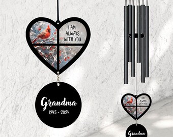 May include: Black wind chime with a heart-shaped ornament featuring a cardinal and the text "I am always with you". The ornament is attached to a round tag with the text "Grandma 1945 - 2024".