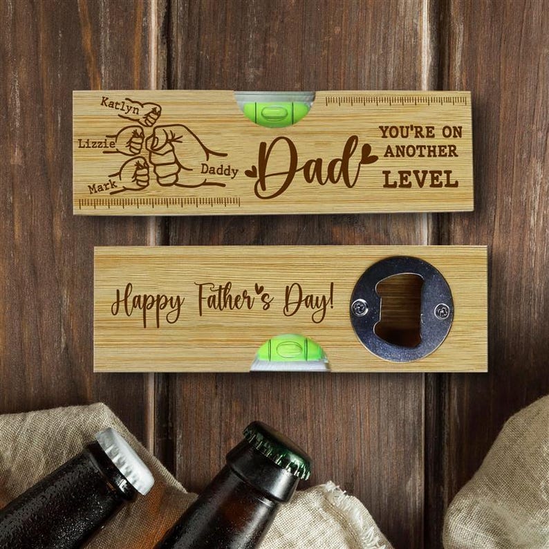 Pu&ograve; includere: Due apribottiglie in legno con livelle a bolla. Uno dice "Pap&agrave;" con nomi e "Sei a un altro livello". L'altro dice "Buona festa del pap&agrave;!" e ha un apribottiglie. Lo sfondo &egrave; una superficie di legno.