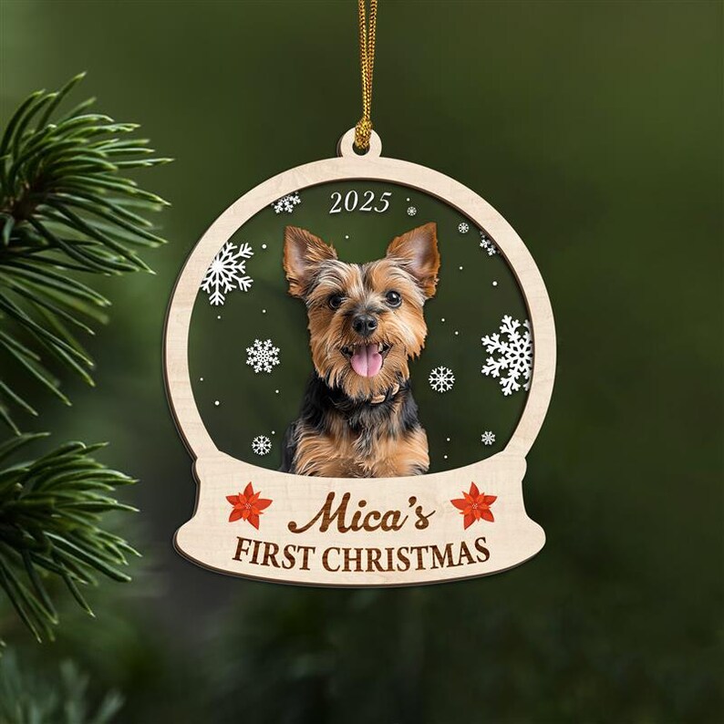 May include: Wooden Christmas ornament featuring a Yorkshire Terrier dog inside a snow globe design. The ornament includes the text "2025" and "Mica's FIRST CHRISTMAS" with snowflake and star accents. A gold string is attached for hanging.