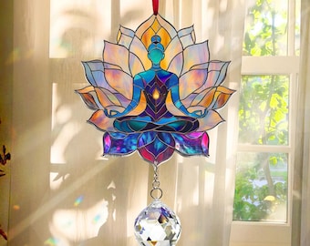 Può includere: Una finestra in vetro colorato appesa con una sfera di cristallo. Il vetro colorato raffigura una figura blu in un fiore di loto con un arcobaleno di colori.