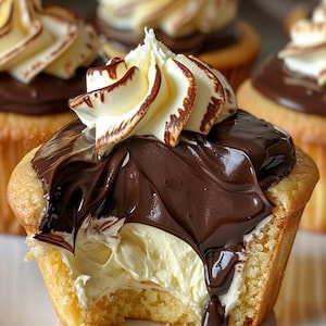 Pode incluir: Um cupcake coberto de chocolate com um redemoinho de glacê branco e uma mordida tirada.