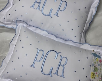 May include: Two white pillowcases with blue embroidered polka dots and blue embroidered initials. The top pillowcase has the initials "ACP" and the bottom pillowcase has the initials "PCR".