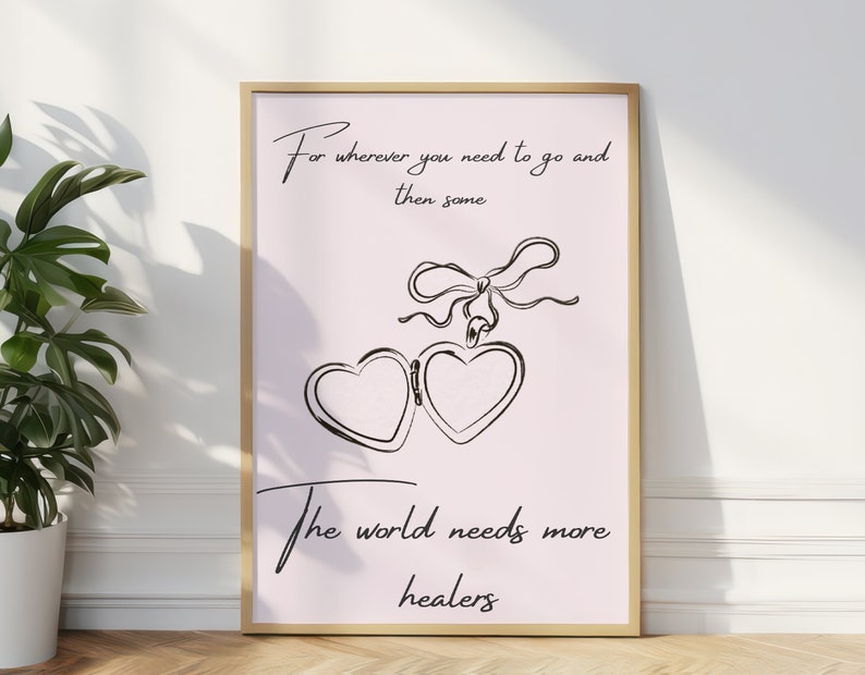 Puede incluir: Una impresi&oacute;n enmarcada con un fondo rosa y texto negro que dice "Para dondequiera que necesites ir y luego algo El mundo necesita m&aacute;s sanadores". La impresi&oacute;n presenta un dibujo de l&iacute;nea negra de un medall&oacute;n en forma de coraz&oacute;n con una cinta.