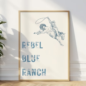 May include: A framed print with a blue and white illustration of a cowboy riding a bucking horse. The text "Rebel Blue Ranch" is printed below the illustration.