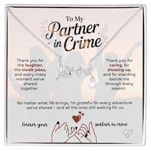 May include: A silver-colored necklace with the word "love" in cursive script, and a small, clear gemstone pendant. The necklace is presented on a white card with the text "To My Partner in Crime."