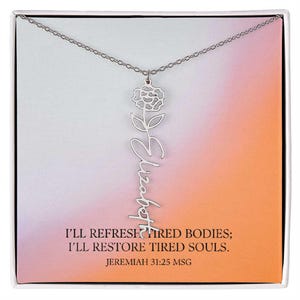 May include: Silver-colored necklace with the name "Elizabeth" in cursive script, featuring a floral pendant. The necklace is displayed on a card with a gradient background of pink, orange, and white, with the text "I'll refresh tired bodies; I'll restore tired souls. Jeremiah 31:25 MSG."