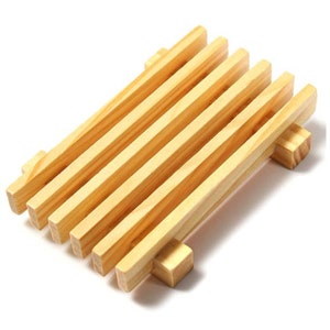 May include: A wooden soap dish with five slats for draining water. The dish is made of natural wood and has a light brown color.