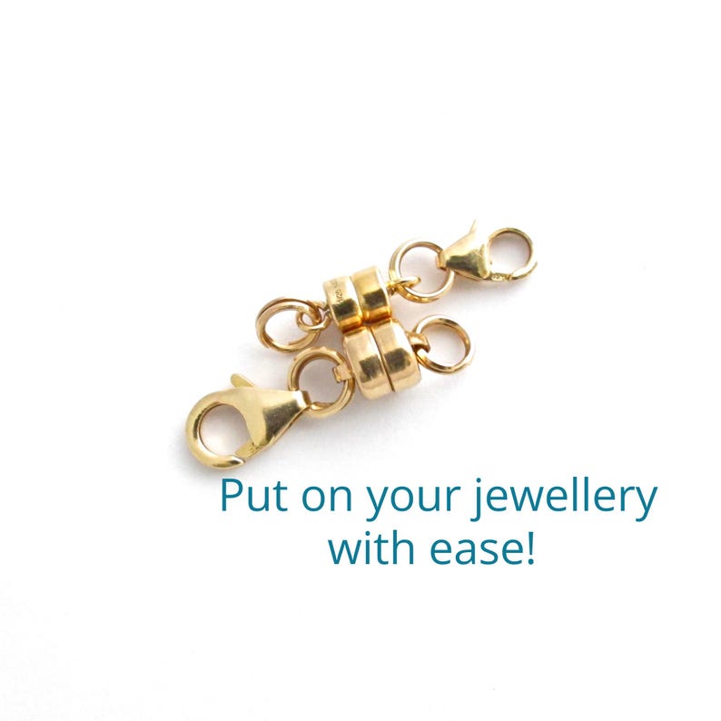 May include: Gold magnetic clasp for jewelry. The clasp is made of two round pieces of metal that connect with magnets. The clasp is attached to two gold chains with lobster claw clasps.
