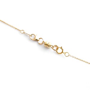May include: A gold chain necklace with a magnetic clasp. The clasp is made of two round pieces of metal that connect together.
