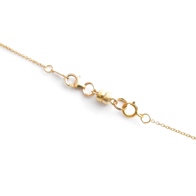 May include: A gold chain necklace with a magnetic clasp. The clasp is made of two round pieces of metal that connect together.