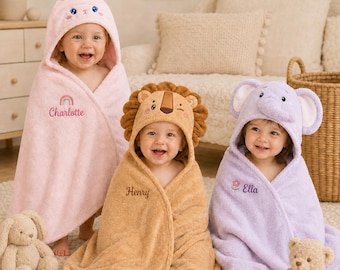 May include: Three hooded bath towels for children. The left towel is light pink with a rabbit hood and the name Charlotte with a rainbow. The center towel is tan with a lion hood and the name Henry. The right towel is light purple with an elephant hood and the name Ella with a flower.