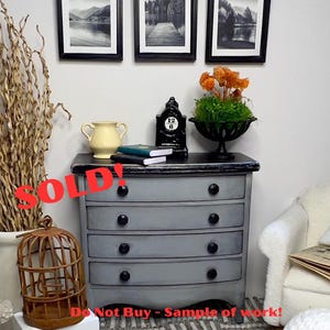 May include: A miniature gray dresser with four drawers and black knobs. The dresser is topped with a yellow vase, a black clock, and small books. A decorative birdcage and framed landscape art are also visible. The word "SOLD!" is written across the image.