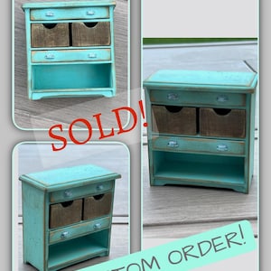 May include: A miniature turquoise cabinet with two brown drawers and a lower shelf. The cabinet has a distressed finish and small silver-colored knobs. The word "SOLD!" is written in red across the image, and "CUSTOM ORDER!" is written in a green banner.