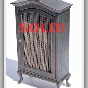 May include: A miniature wooden cabinet with a dark finish, featuring a wire mesh door and decorative legs. The word "SOLD!" is prominently displayed in red across the front. Text at the bottom reads "Not for sale - Do not buy!"