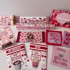 May include: A collection of Mother's Day themed gifts, including chocolate bars, lip balm, and coasters. The items feature cherry and bow designs, with text like "Happy Mother's Day" and "Mum, You are our Cherry on top."