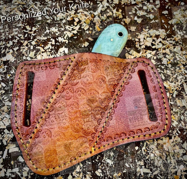 May include: A brown leather knife sheath with a decorative pattern and a light blue knife blade sticking out of the top.