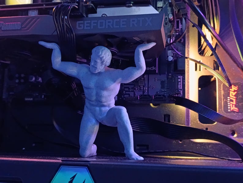 K&ouml;nnte beinhalten: Eine graue Plastikfigur einer Person, die ein Computerbauteil mit dem Text "GEFORCE RTX" hochh&auml;lt. Die Figur steht vor einem Computer-Motherboard mit verschiedenen Kabeln und Dr&auml;hten.