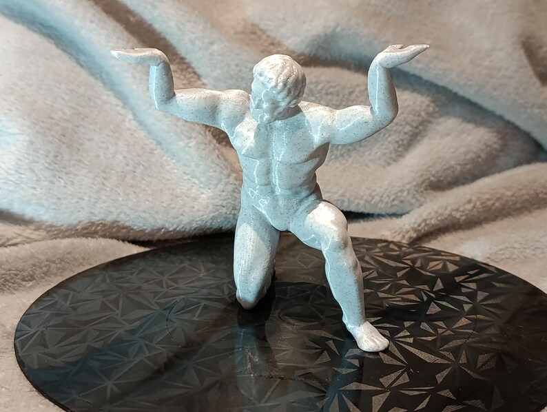 K&ouml;nnte beinhalten: Eine wei&szlig;e, 3D-gedruckte Figur eines Menschen in einer knienden Pose mit erhobenen Armen. Die Figur steht auf einer schwarzen, gemusterten Oberfl&auml;che.