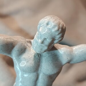 K&ouml;nnte beinhalten: Eine wei&szlig;e 3D-gedruckte Figur eines muskul&ouml;sen K&ouml;rpers mit einer strukturierten Oberfl&auml;che. Die Figur ist mit einem erhobenen Arm und dem anderen Arm, der im Ellbogen gebeugt ist, dargestellt.