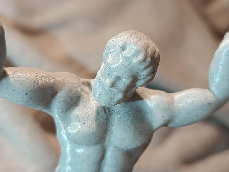 K&ouml;nnte beinhalten: Eine wei&szlig;e 3D-gedruckte Figur eines muskul&ouml;sen K&ouml;rpers mit einer strukturierten Oberfl&auml;che. Die Figur ist mit einem erhobenen Arm und dem anderen Arm, der im Ellbogen gebeugt ist, dargestellt.