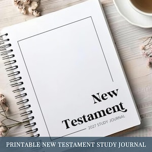May include: A white spiral-bound journal with a black rectangular border on the cover. The text reads New Testament 2027 Study Journal in a bold serif font. The journal features a clean, minimalist design with black wire binding on the left side.